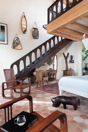A bedroom with a wooden staircase, a bed, a dining table, and a chair. - Hotel Boutique Casa del Limonero - Adults only (Seville)