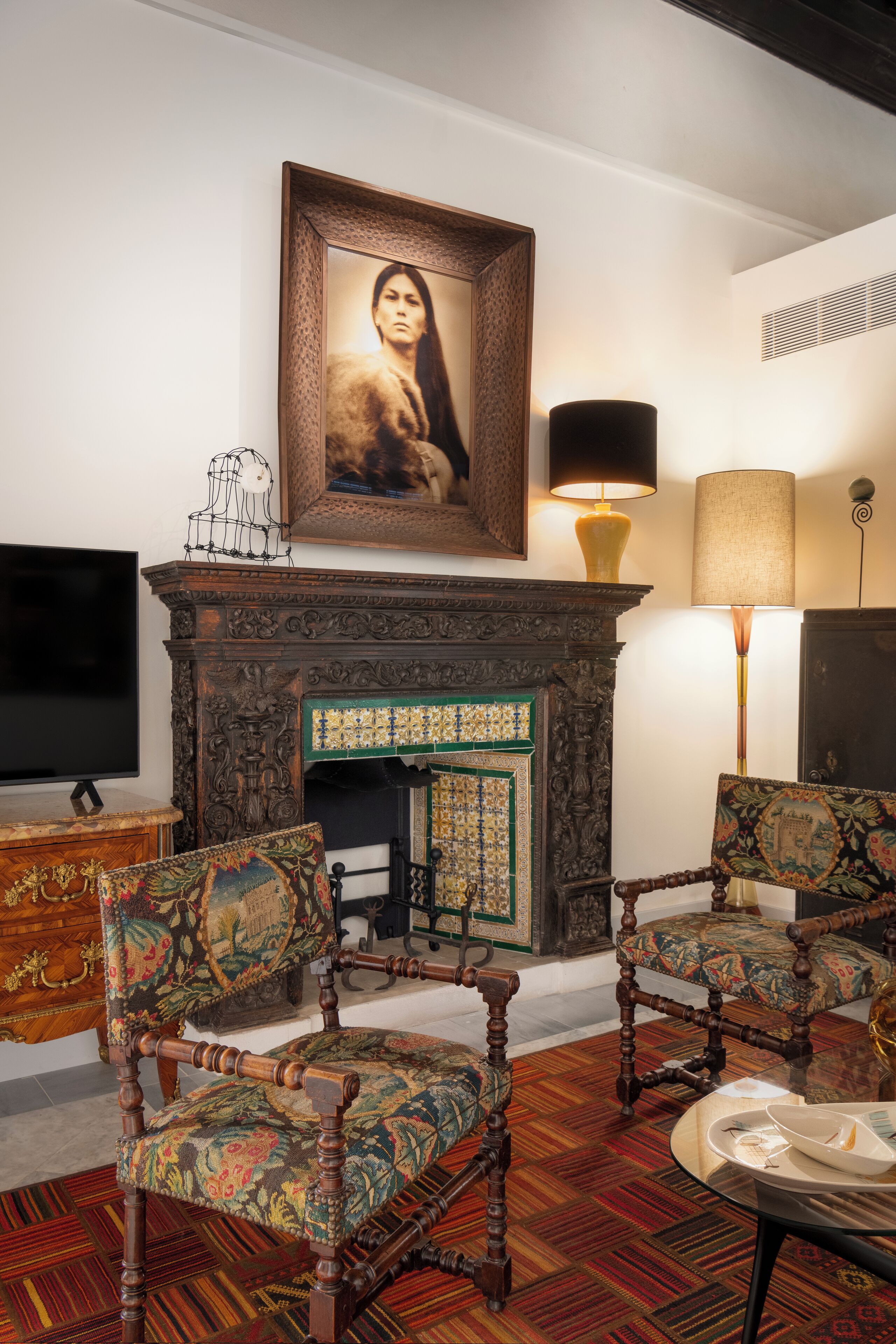 Una habitación tradicional con chimenea, dos sillones tapizados, un televisor y una lámpara.