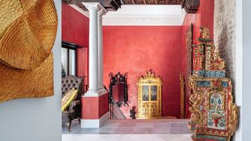 A room with a red wall, a golden ornate cabinet, and a white column.