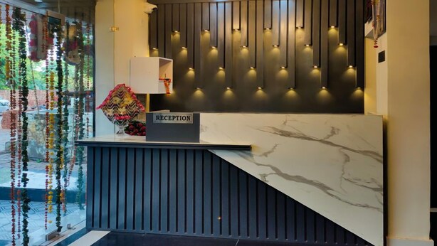 Un área de recepción con mostrador de mármol, candelabro y panel de luz empotrado.