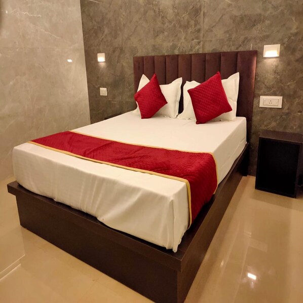 Une chambre d’hôtel moderne avec un grand lit, une tête de lit en bois et un mur en marbre.