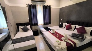 Habitación de hotel con dos camas, un ventanal con cortinas, un aire acondicionado y un minibar.