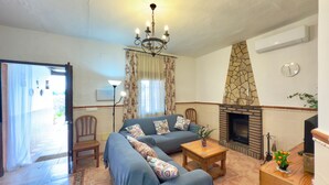 Una sala de estar con sofá, una mesita, chimenea y candelabro.