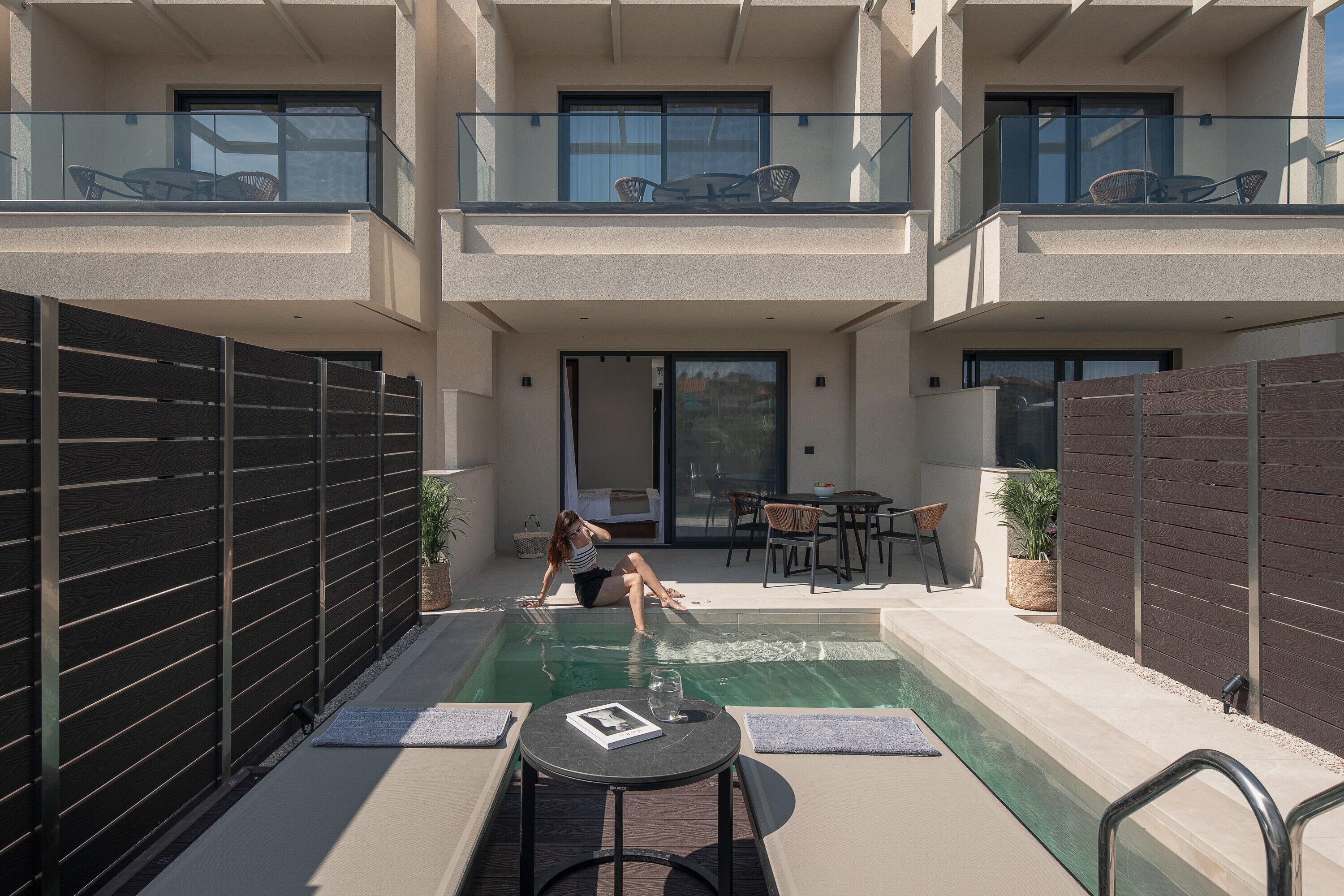 Un appartement moderne doté d’une piscine, d’un espace extérieur aménagé et d’un balcon avec mobilier.