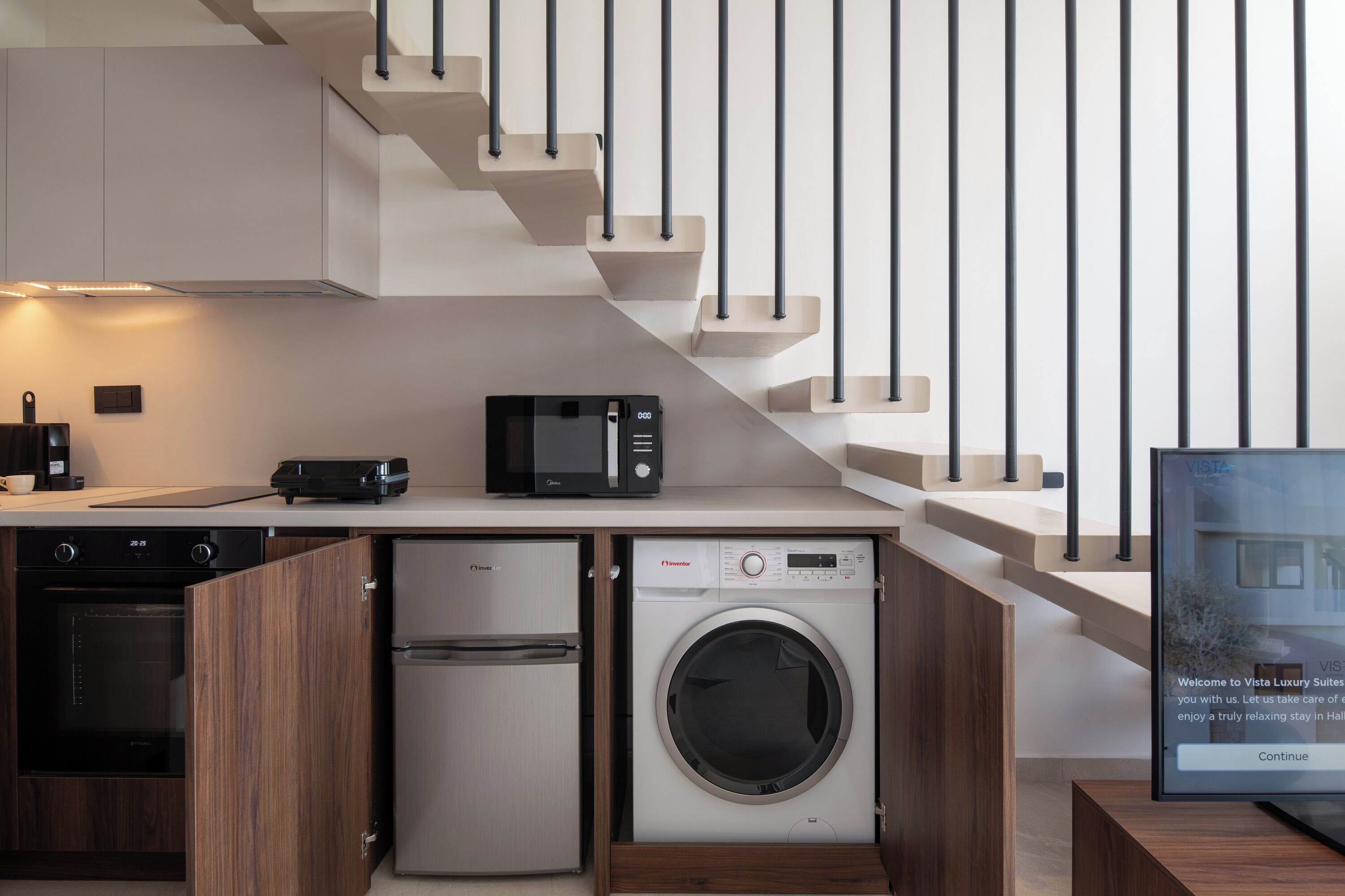 A modern kitchen with built-in appliances, a microwave, a dishwasher, and a washing machine.