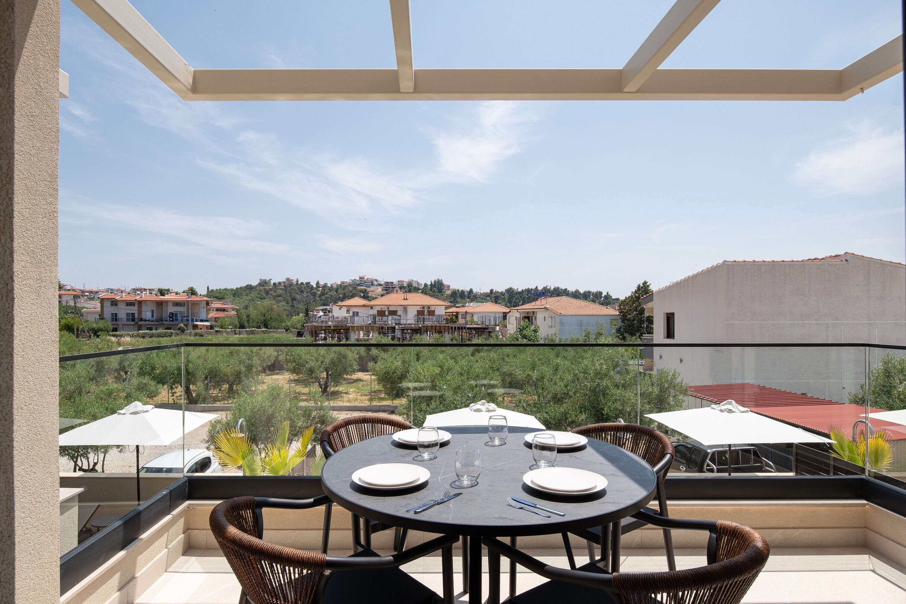 A balcony with a table set for four, overlooking a residential area with houses and trees.