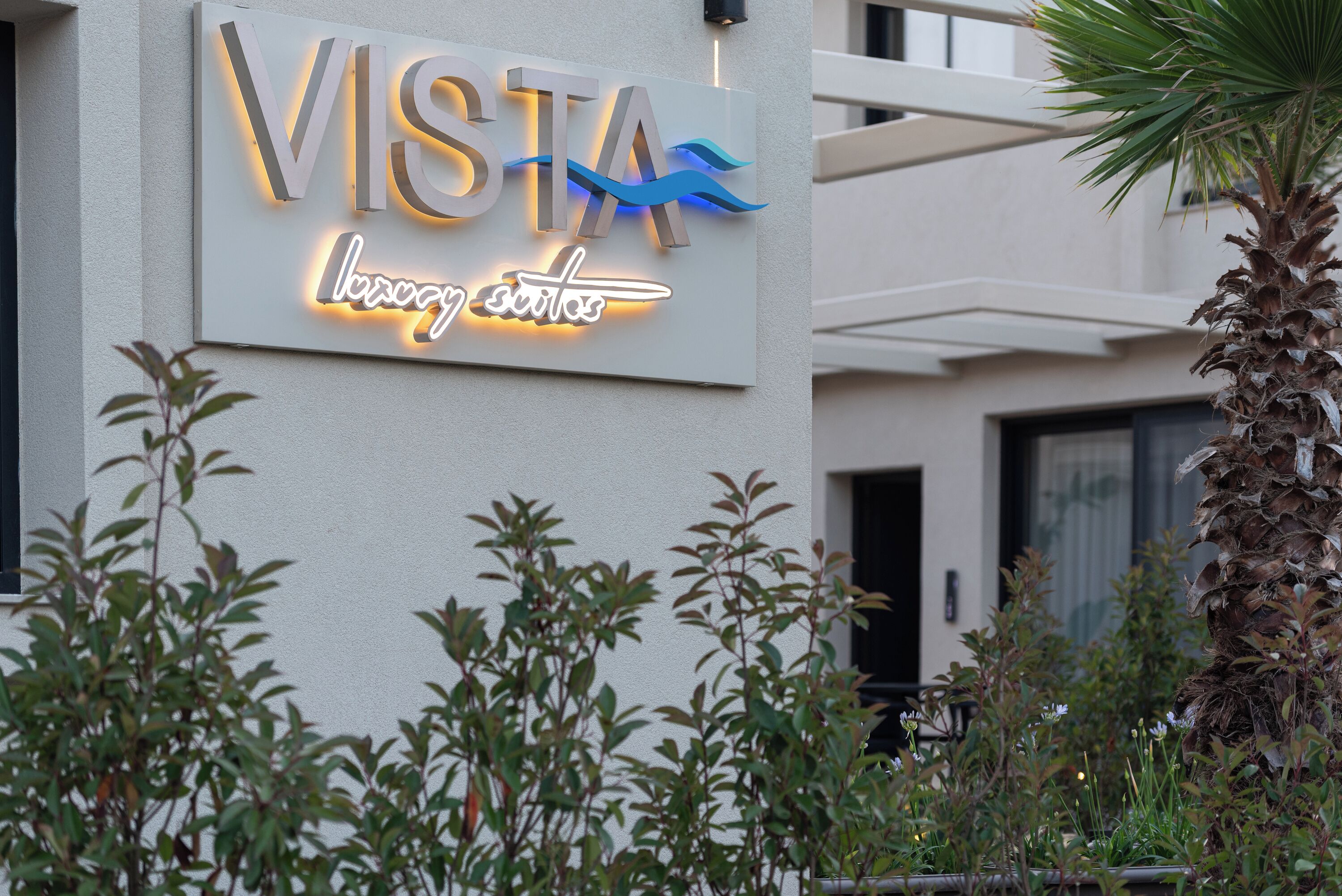 A sign for "VISTA" with a neon wave design and the words "luxury resort" below it.