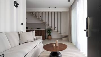 A modern living room with a sofa, a coffee table, and a staircase leading to an upper level.