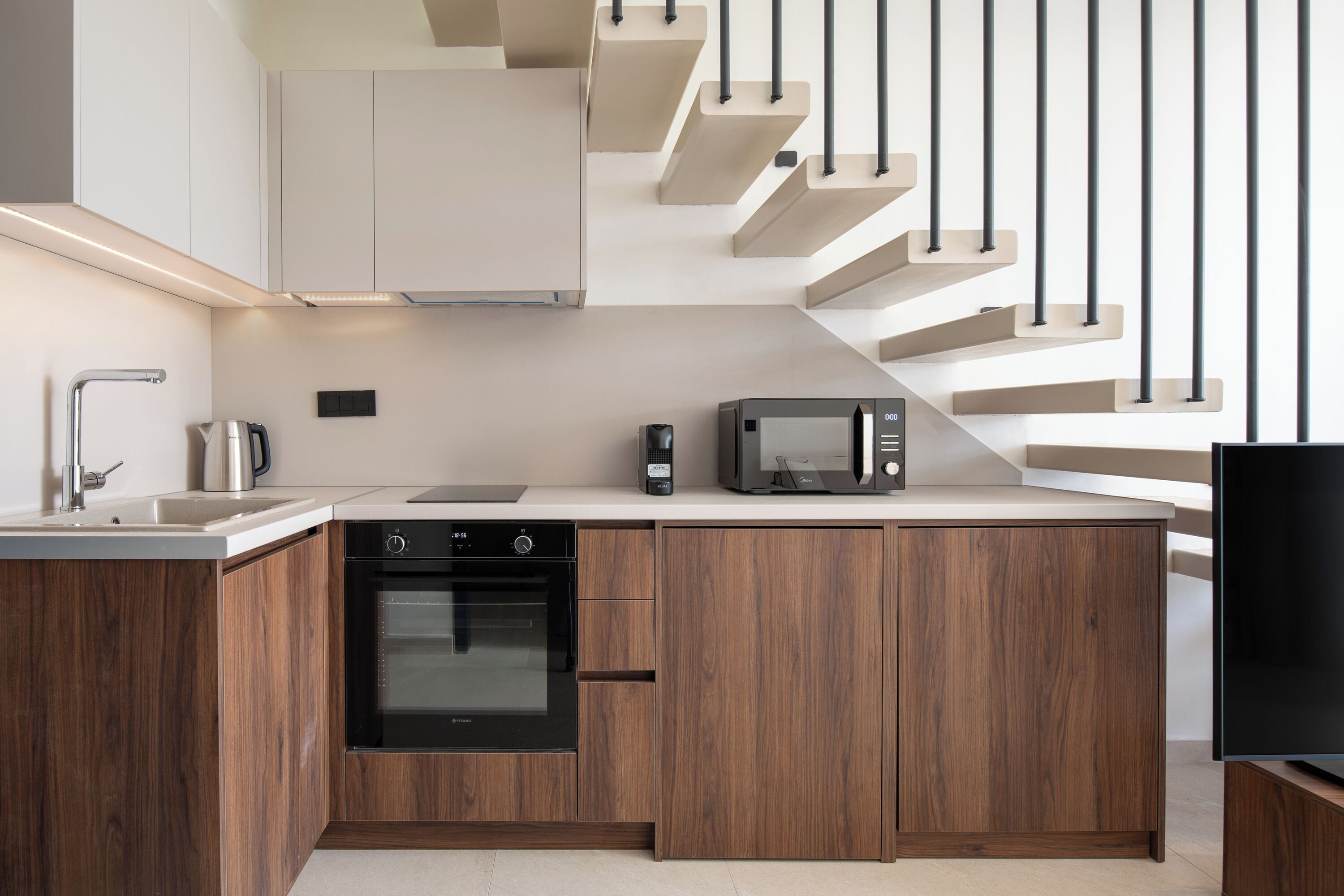 A modern kitchen with wooden cabinets, a built-in oven, a microwave, and a coffee maker.