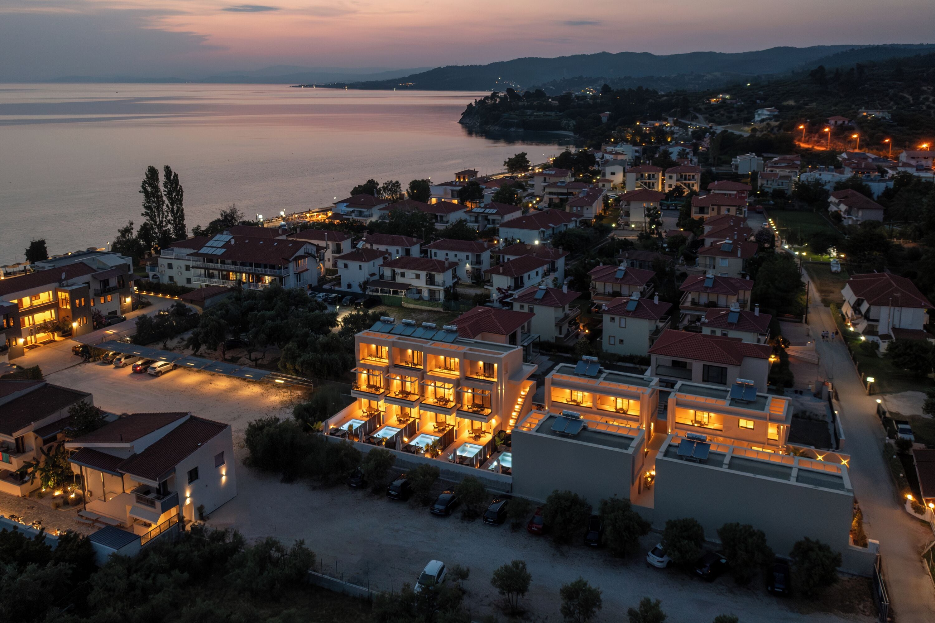 Une ville côtière qui abrite un hôtel imposant, doté de plusieurs étages, d’un parking et offrant une vue sur la mer.
