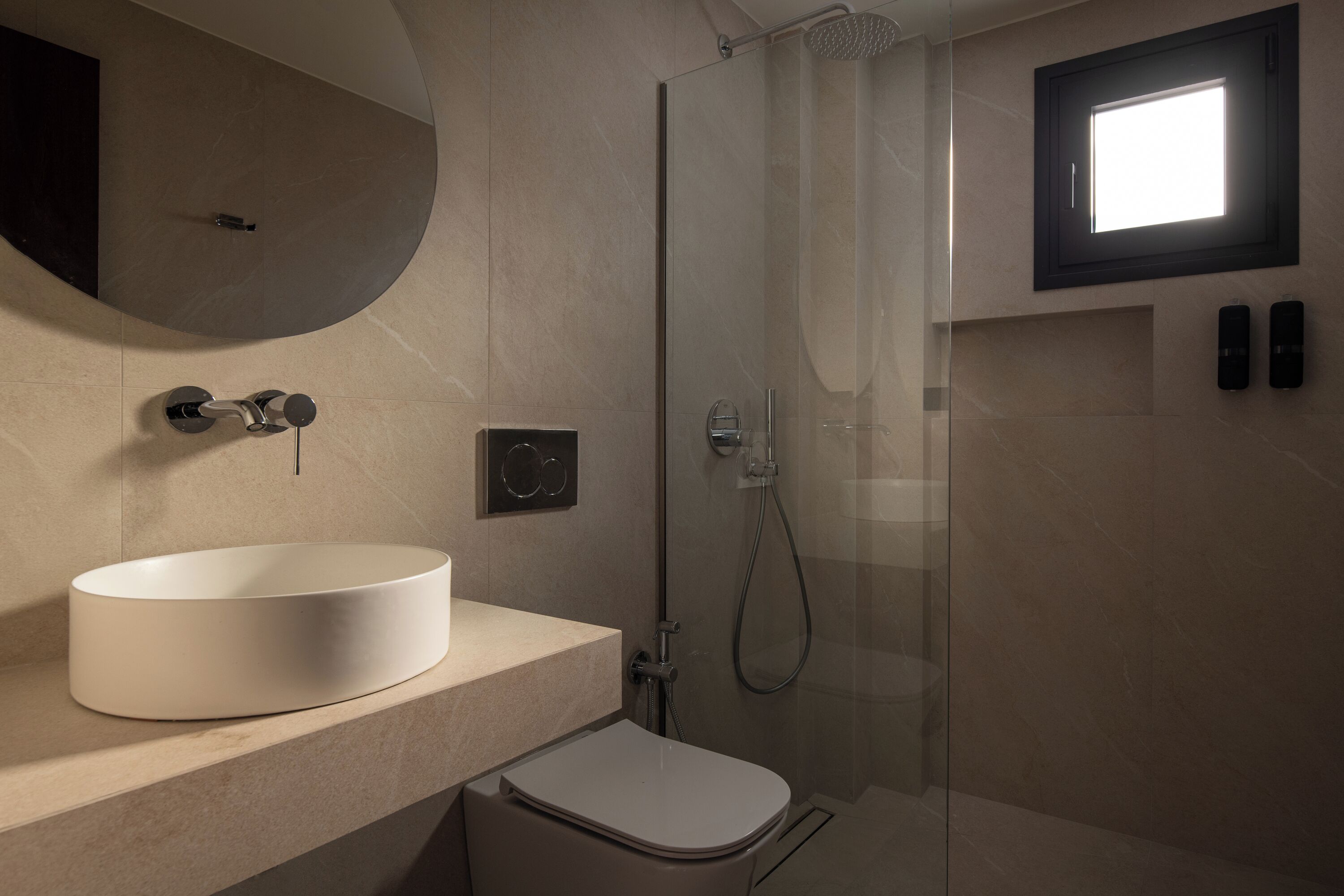 A modern bathroom with a round sink, a toilet, and a glass-enclosed shower.