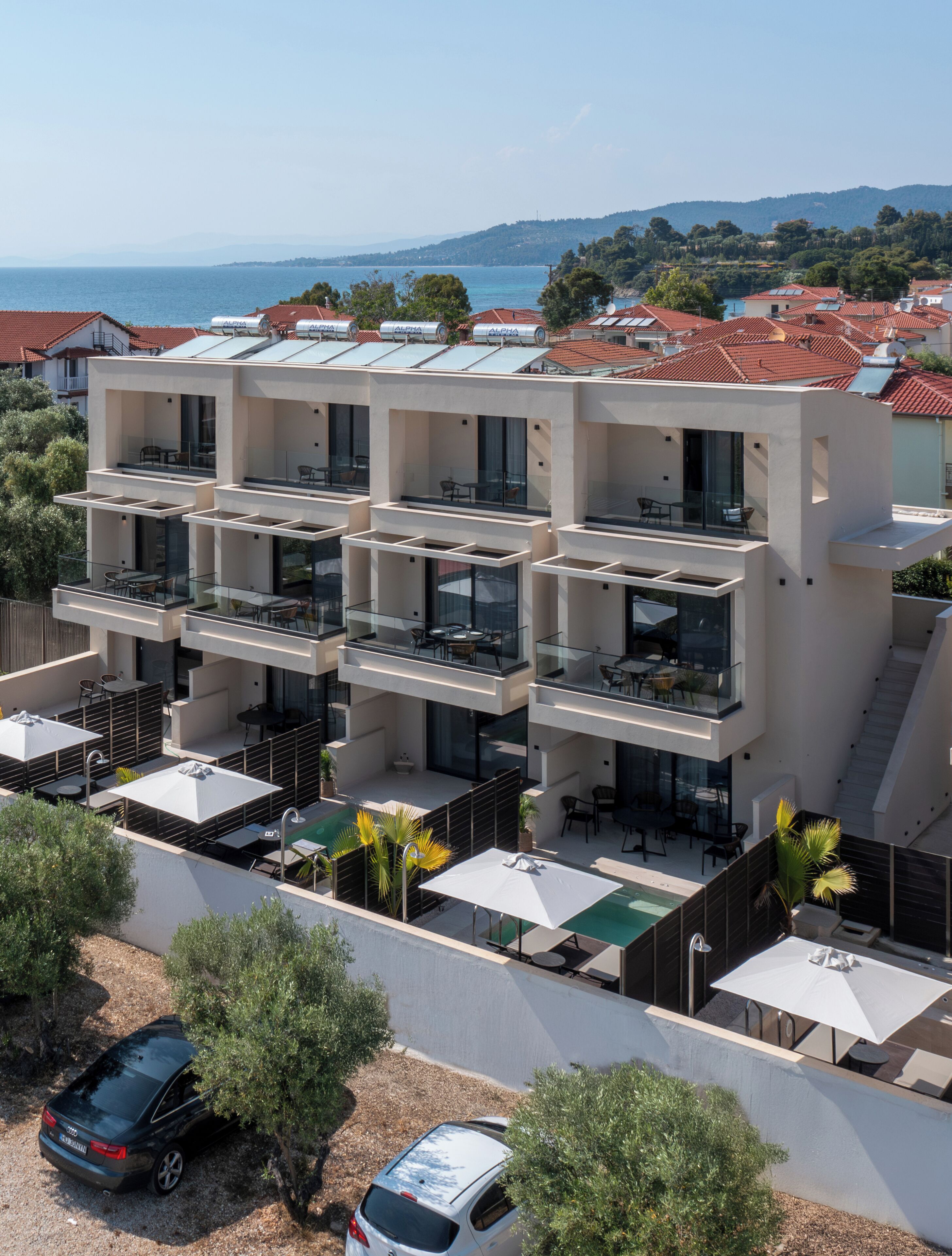 A modern multi-story building with balconies, outdoor seating, and a pool area.