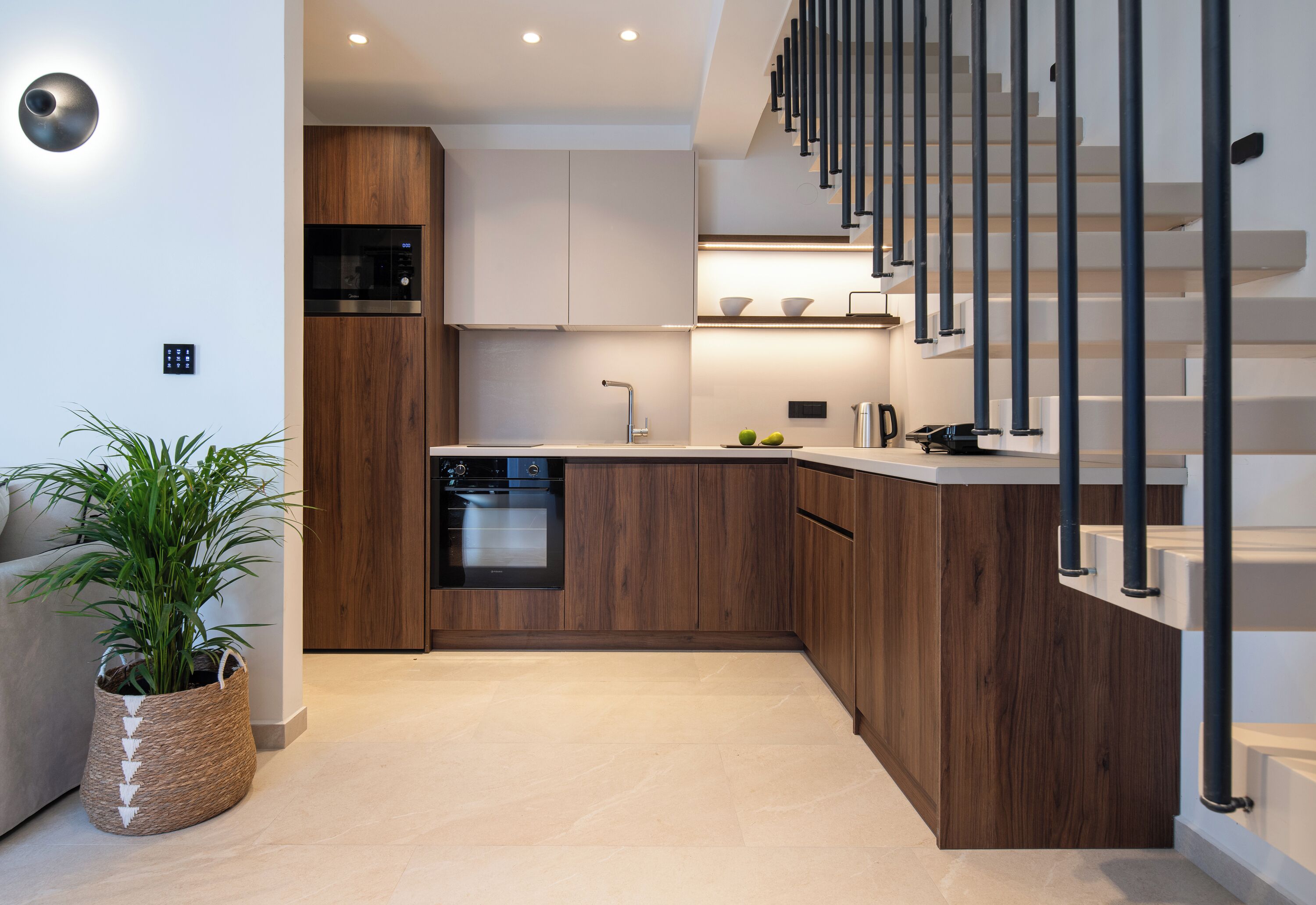 A modern kitchen with wooden cabinets, a built-in oven, and a stainless steel microwave.