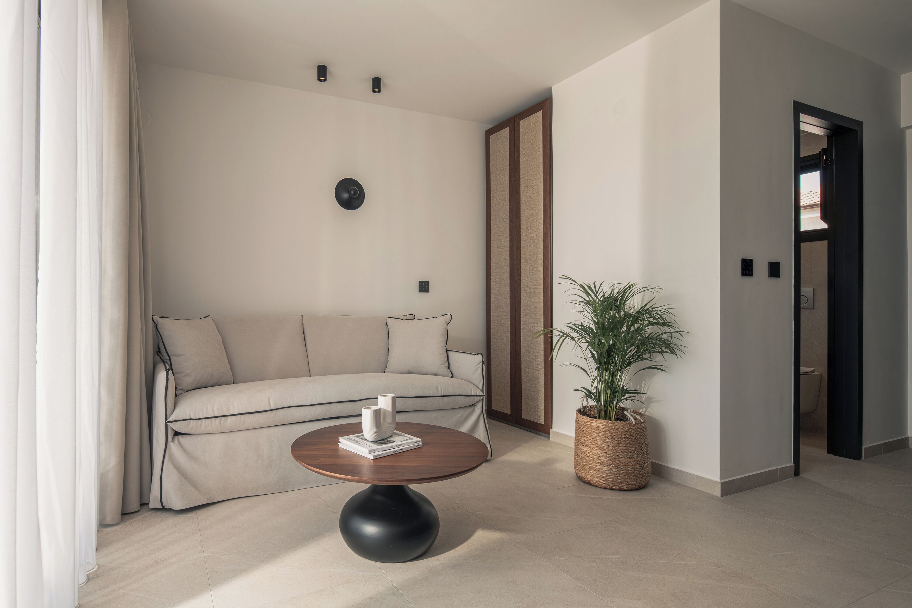 Un salón moderno con un sofá beige, una mesa de centro redonda y una planta en maceta.
