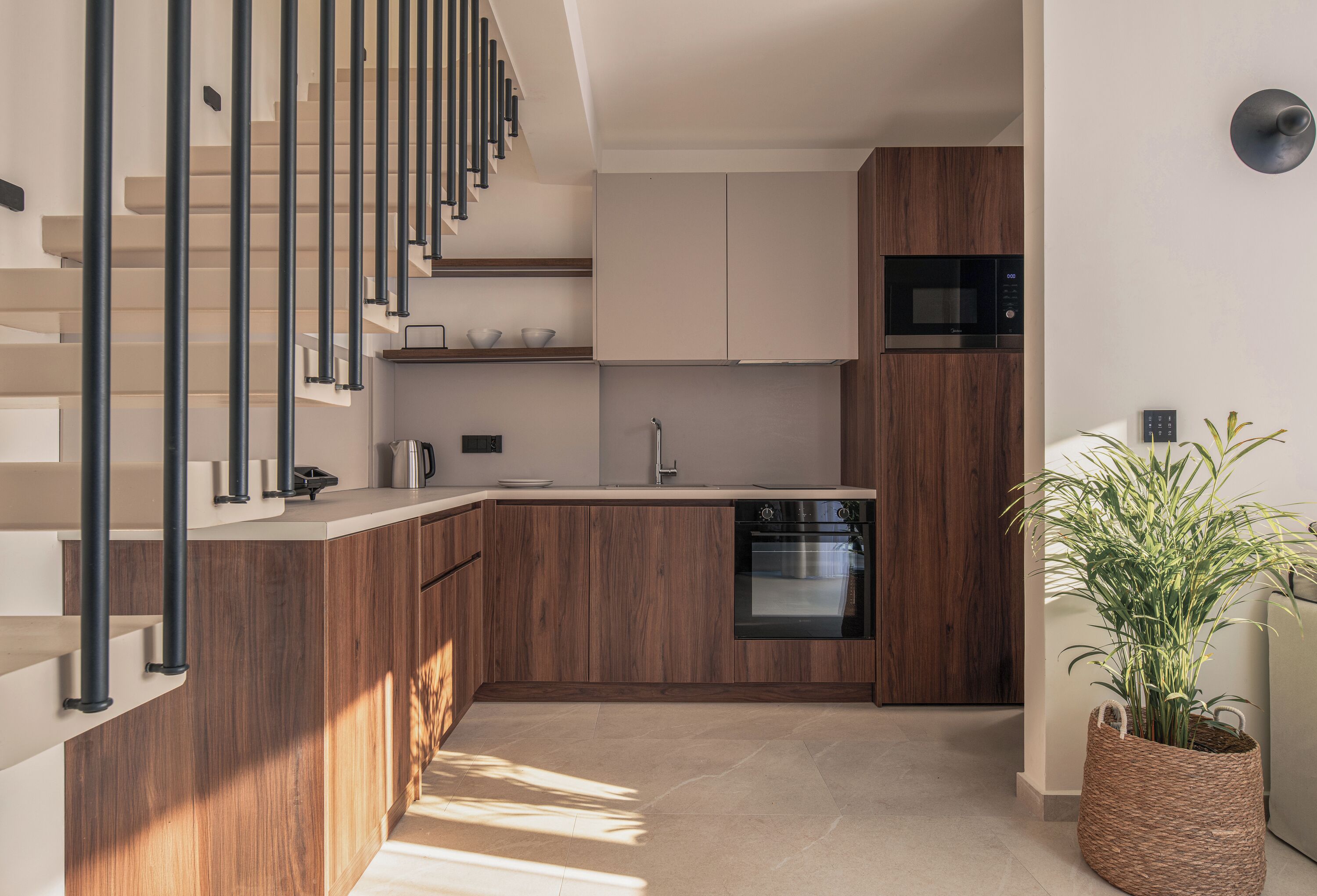 Una cocina moderna con armarios de madera, horno empotrado y microondas de acero inoxidable.