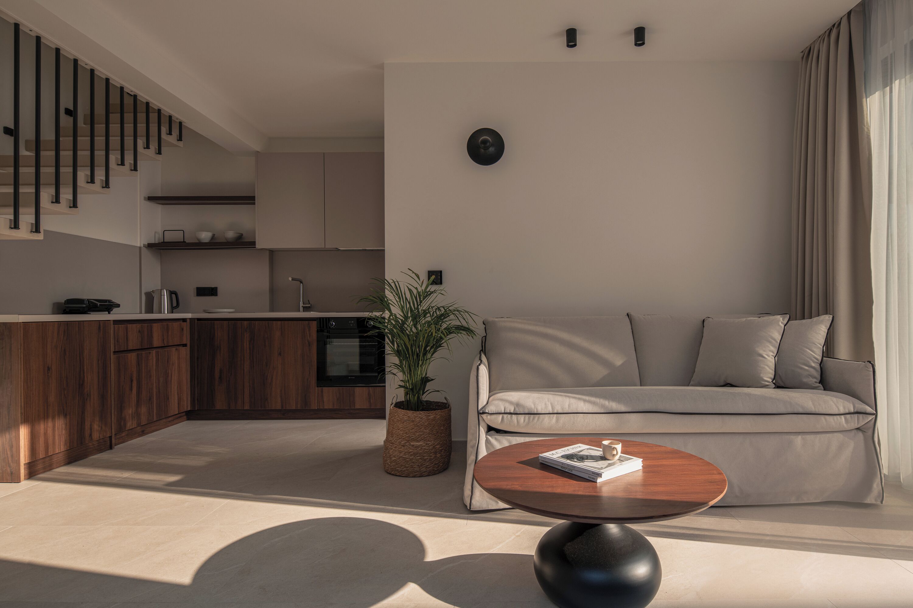 A modern living room with a sofa, a coffee table, and a kitchen area in the background.