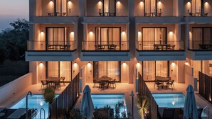 A modern multi-story building with balconies, outdoor seating, and a swimming pool.