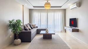 Una sala de estar moderna con un sofá seccional, una mesa de centro, una planta en maceta y un televisor de pantalla plana montado en la pared.