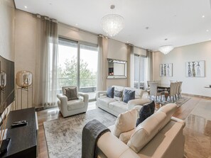 A spacious living room with a large sofa, a dining area with a table and chairs, and a balcony with a view. - Dream Palm Residence 3BR Luxury Apartment on Palm Jumeirah (Dubai)