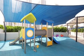 A children's play area with a slide, climbing structures, and a soft play surface. - Bloomfields 2BR in Bridges Al Reem (Abu Dhabi)