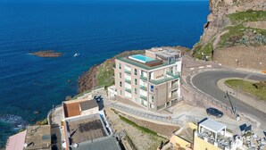 A coastal building with a swimming pool, a winding road, and a view of the sea. - Sardinia Re - Miramare 14 Sea View (Castelsardo)