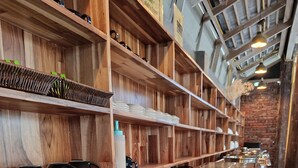 A buffet area with wooden shelves, a variety of dishes, and a plate of sushi rolls. - Vang Luang Hotel (Luang Prabang)
