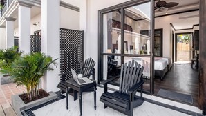 A modern hotel room with a large glass door, a bed, a desk with a laptop, and a chair. - Vang Luang Hotel (Luang Prabang)