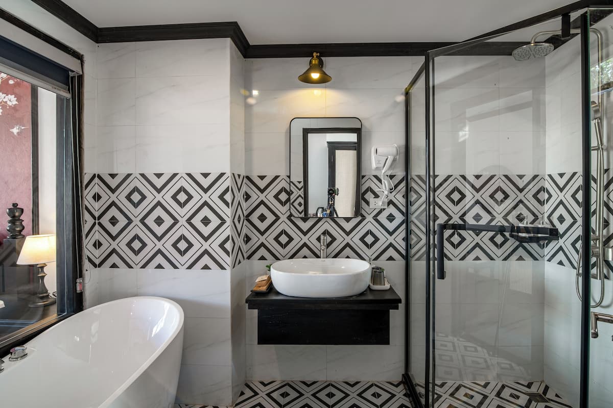A modern bathroom with a freestanding bathtub, a vanity with a large mirror, and a shower area.
