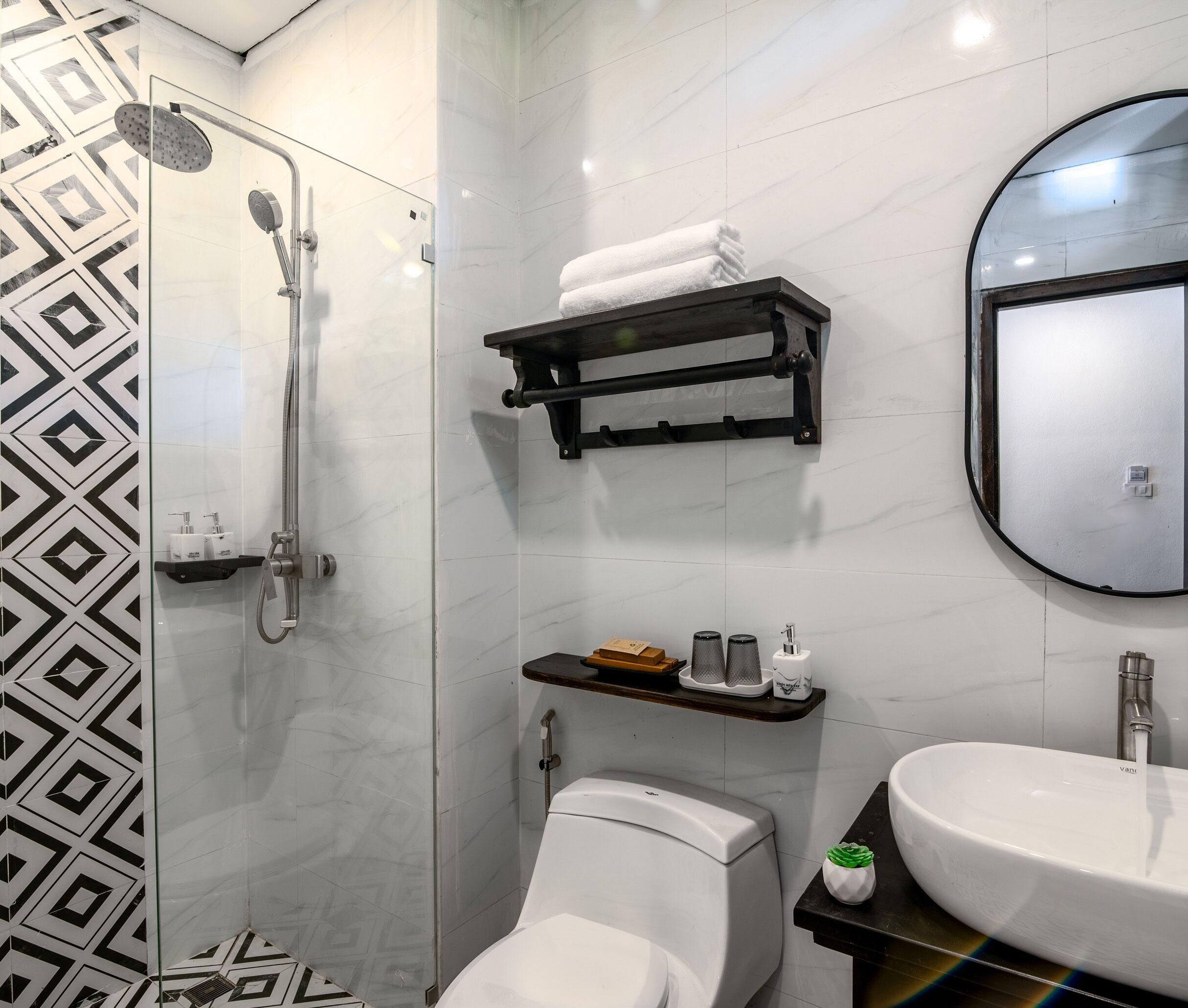 A modern bathroom with a glass-enclosed shower, a toilet, a sink, and a towel rack.