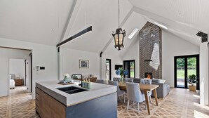 A spacious kitchen with a large island, a dining area with a wooden table and chairs, and a fireplace. - The Mist, Luxury Farm Retreat w/ Fireplace & Hot tub | Southern Highlands (Exeter)