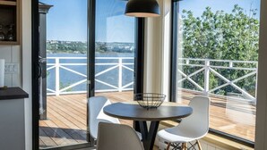 A room with a large window, a round table with two chairs, and a hanging light fixture.