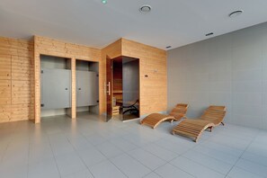 Un moderno spa con paneles de madera, zona de sauna y tumbonas de madera.