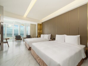 A hotel room with two beds, a large window with a view of the sea, and a seating area with a table and chairs. - Orient Luxury Hotel-KenTing (Hengchun)