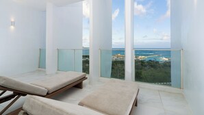 A balcony with two sunbeds, a glass railing, and a view of the sea and cityscape. - Orient Luxury Hotel-KenTing (Hengchun)