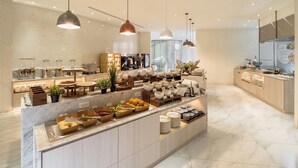 A modern kitchen with marble countertops, a central island with bowls and utensils, pendant lighting, and a view of the adjacent dining area. - Orient Luxury Hotel-KenTing (Hengchun)