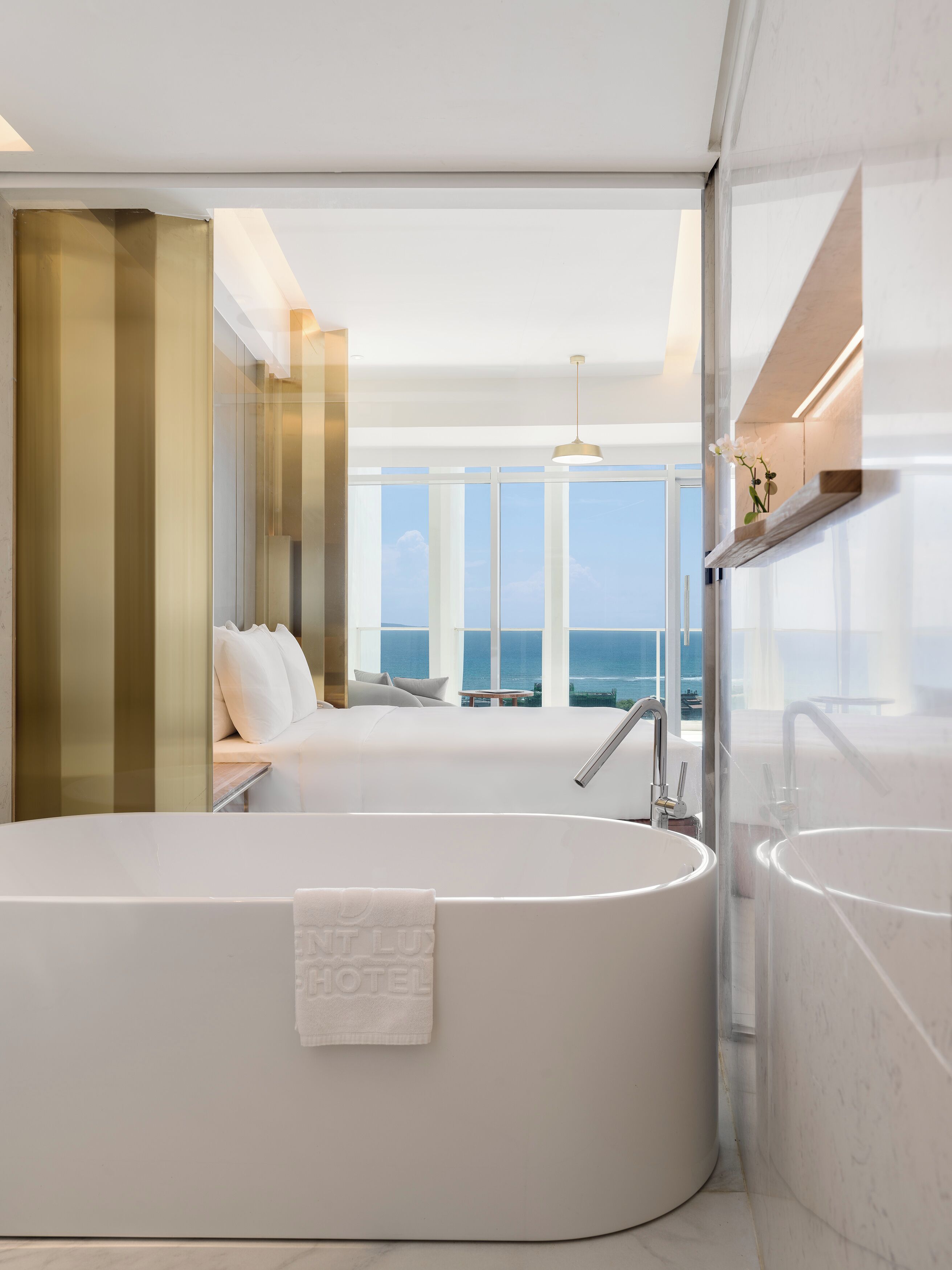 A modern bathroom with a large bathtub, a separate sink, and a view of the ocean.