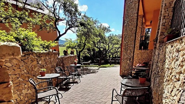 An outdoor patio with stone walls, metal chairs, and tables. - Harmónia Wellness Villa (Szilvasvarad)