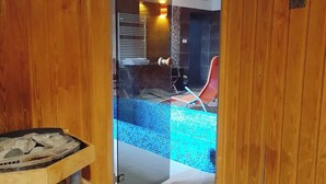 A wooden door leading to a room with a tiled floor, a glass partition, and a red chair. - Harmónia Wellness Villa (Szilvasvarad)