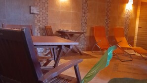 A room with a dining table, chairs, and a plant in the foreground. - Harmónia Wellness Villa (Szilvasvarad)
