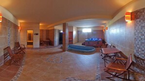 A spa area with a hot tub, wooden chairs, and a tiled floor. - Harmónia Wellness Villa (Szilvasvarad)