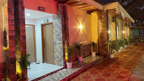 Un edificio de fachada roja, con un letrero que indica 'TOILETS' y 'LADIES', y un área exterior cubierta con plantas en macetas.
