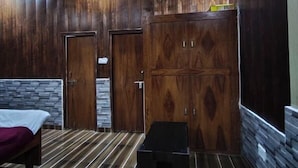 Una habitación con cama, ventilador de techo, paneles de madera y una pared de acento de piedra.
