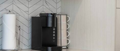 A modern kitchen with a black coffee machine, a paper towel holder, and a white marble countertop.