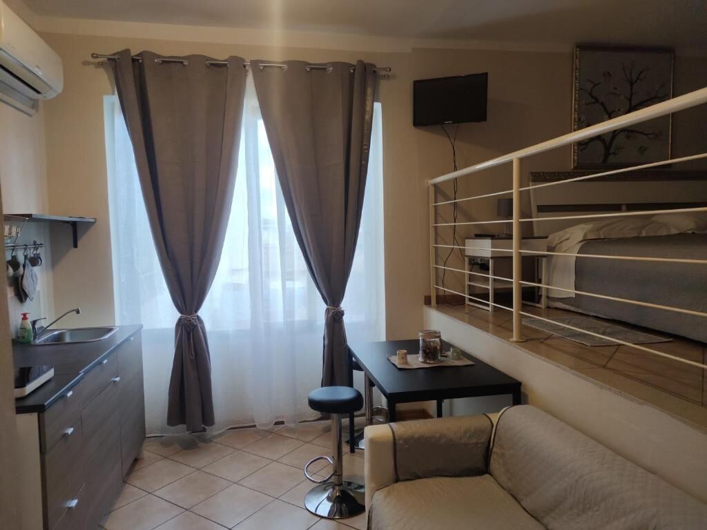 A compact hotel room with a kitchenette, a sofa, a small table, and a bunk bed.