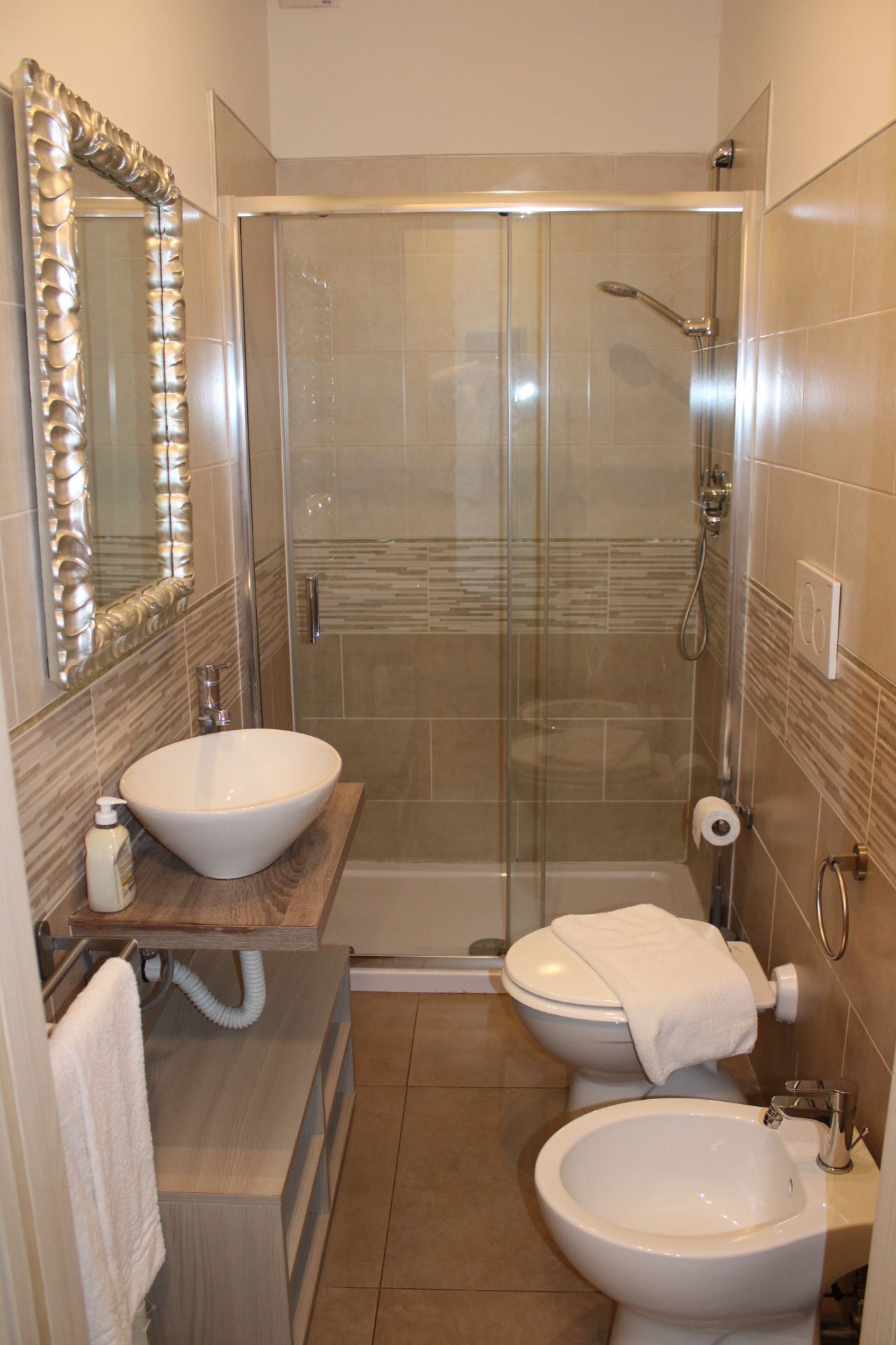 Une salle de bain moderne dotée d’une douche à parois de verre, de deux lavabos, de toilettes et d’un grand miroir.