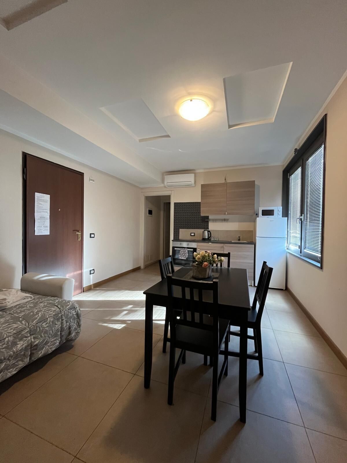A compact living space with a dining area, kitchenette, and a bed.