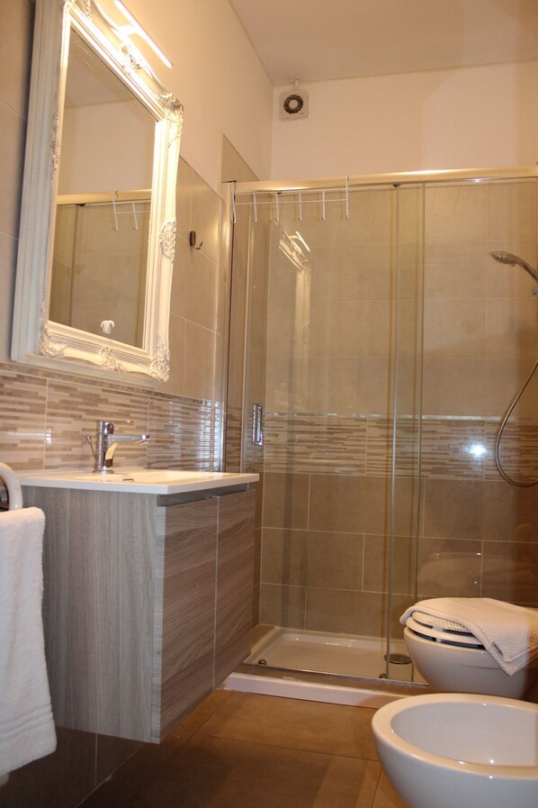 A modern bathroom with a glass-enclosed shower, a vanity with a mirror, and a toilet.