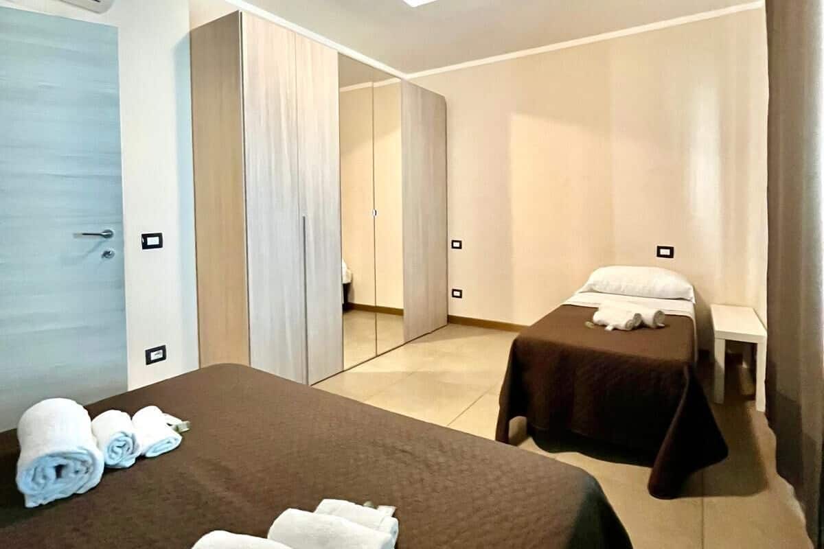 A hotel room with two beds, a large mirror, and a ceiling light.