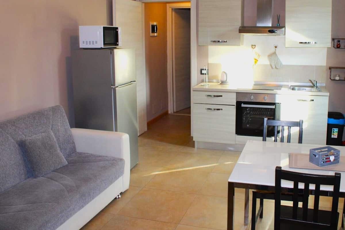 A compact living space with a sofa, kitchenette, and a dining area.