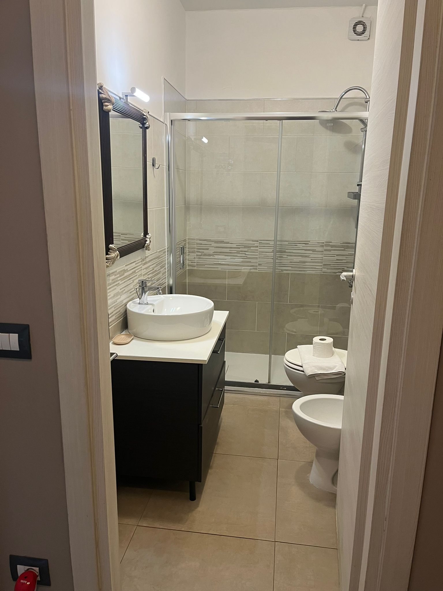 A modern bathroom with a glass-enclosed shower, a white sink, and a toilet.